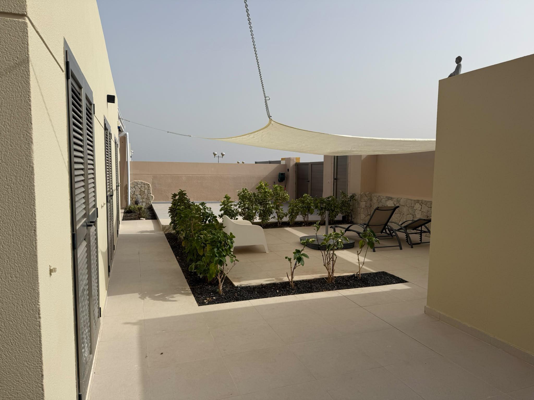Überdachte Terrasse mit Sonnensegel und Loungemöbeln